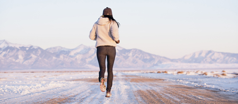 Rear view of woman running in winter landscape, Colorado, USA