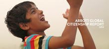 Young indian boy in multi-colored striped t-shirt, laughing and clapping his hands as he looks at something he sees in the sky.